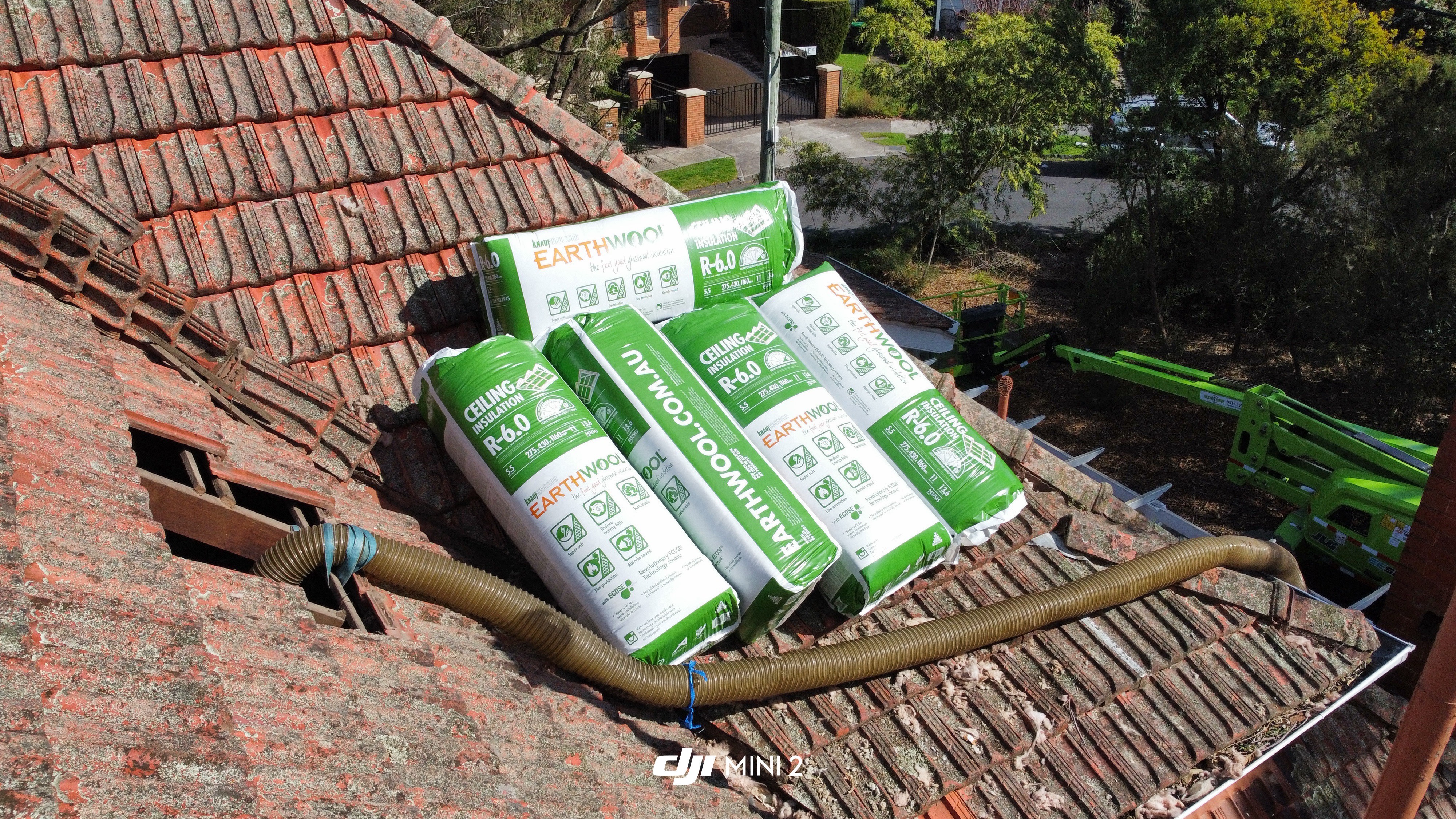 Aerial view of Knauf Earthwool R6.0 ceiling insulation bags stacked on a Melbourne tile roof, ready for crew to lift tiles and install into the ceiling cavity